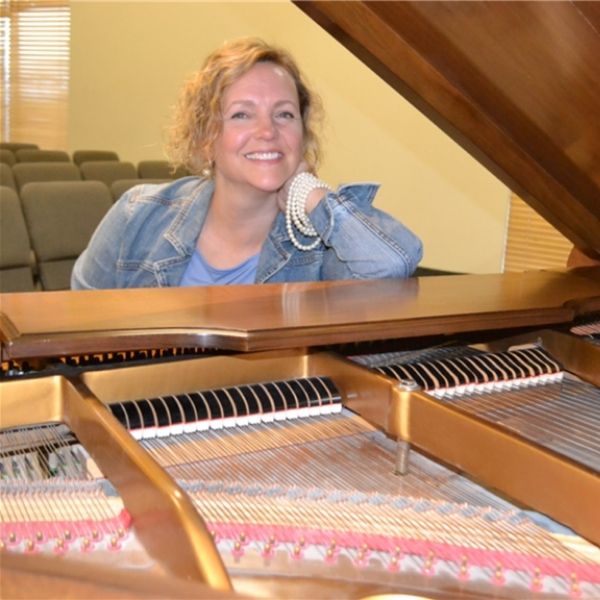Woman smiling sitting in front of a piano