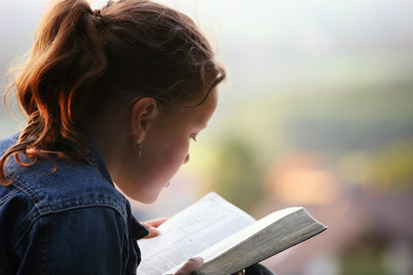 An image of young child reading the bible